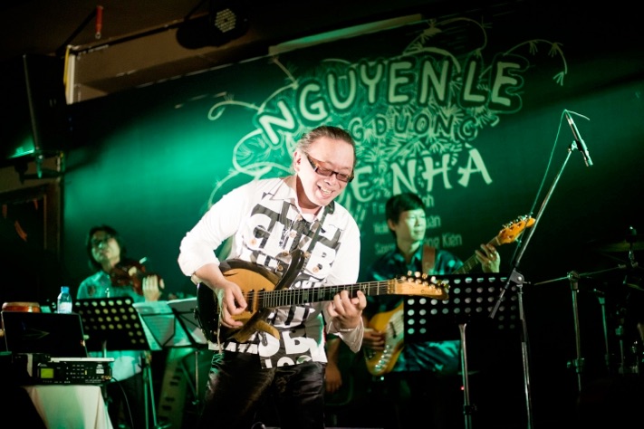Nguyên Lê chơi guitar trước phông sân khấu Quê nhà